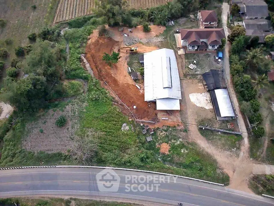 Aerial view of rural property with large building and surrounding greenery.