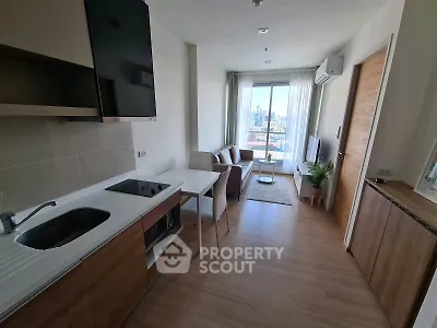 Modern open-layout living room with kitchen, featuring city view and stylish decor.