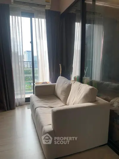 Cozy living room with a plush sofa and large window offering a scenic view, perfect for relaxation.