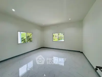 Spacious empty room with large windows and glossy white tile flooring.
