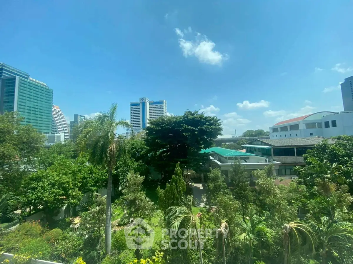 Stunning cityscape view with lush greenery and modern buildings under a clear blue sky.