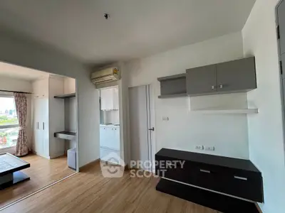 Modern apartment interior with wooden flooring and built-in storage, featuring an open layout and air conditioning.