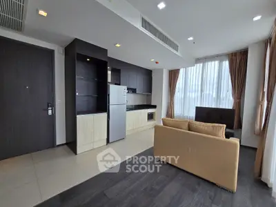 Modern open-layout living room with sleek kitchen and large windows in a stylish apartment.