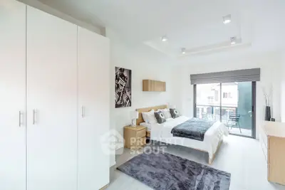 Modern bedroom with large window and stylish decor in a contemporary apartment.