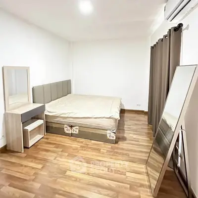 Spacious bedroom with wooden flooring and modern furniture