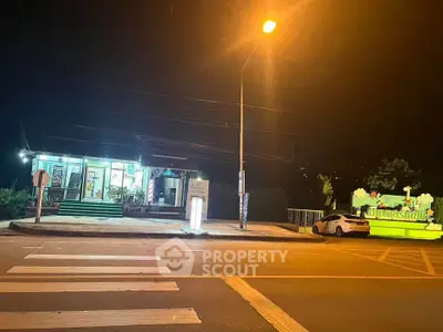Charming night view of a small commercial property with bright signage and street lighting.