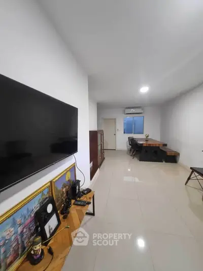 Spacious modern living room with sleek TV setup and elegant dining area.