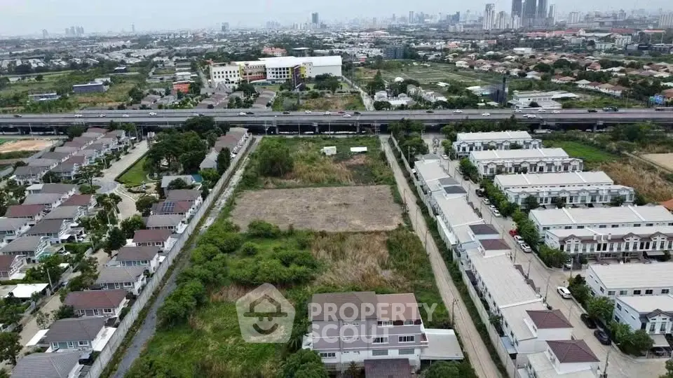 Aerial view of residential area with houses and open land, showcasing urban development potential.