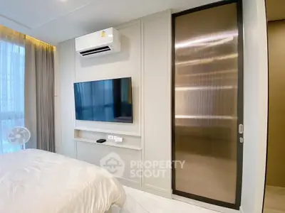 Modern bedroom with sleek TV setup and air conditioning in a stylish apartment.