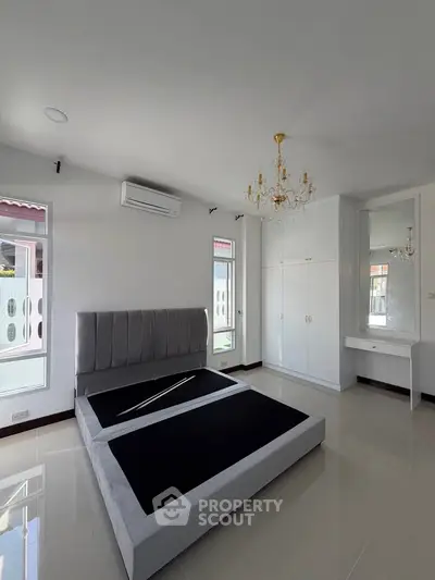 Spacious bedroom with elegant chandelier and modern bed frame