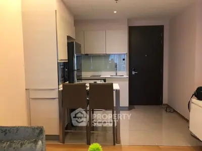Modern kitchen with sleek cabinetry and breakfast bar seating in a cozy apartment.