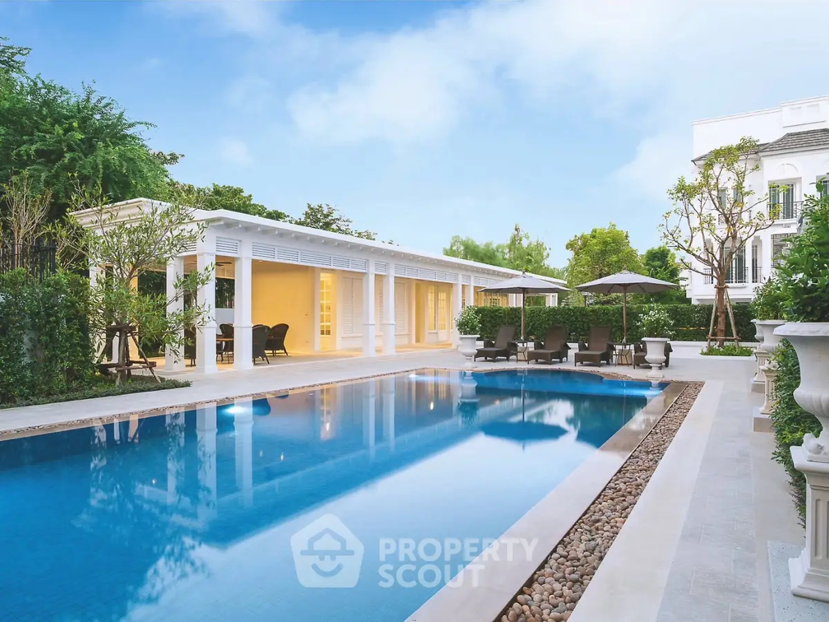 Luxurious outdoor pool area with elegant seating and lush greenery, perfect for relaxation and entertainment.