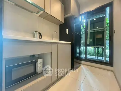 Modern kitchen with sleek cabinetry and appliances, featuring a microwave and kettle.
