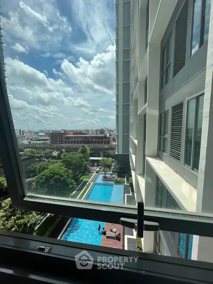 Stunning view from a high-rise apartment overlooking a luxurious pool and cityscape.