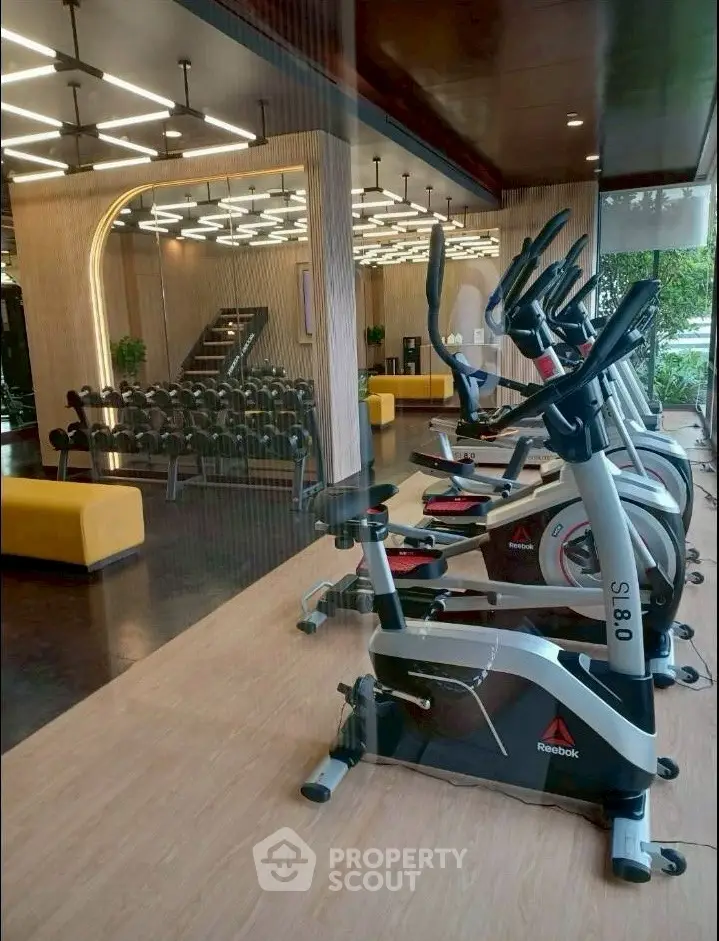Modern gym with exercise bikes and weights in luxury apartment complex