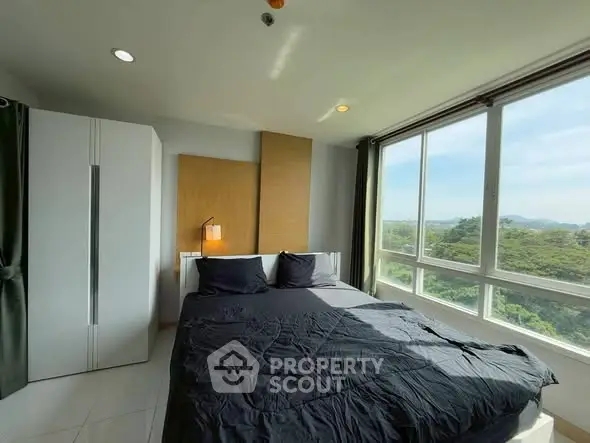 Bright bedroom with large windows offering scenic views and modern furnishings.