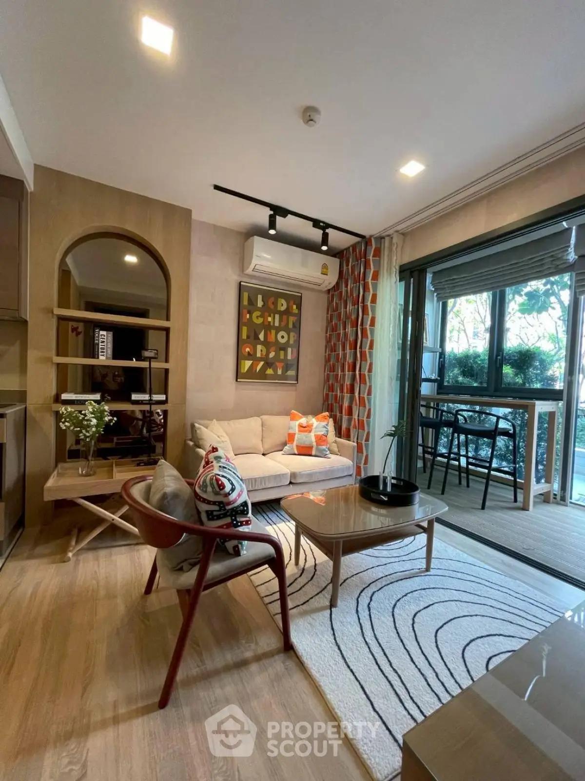 Modern living room with stylish decor and large windows opening to a balcony with garden view.