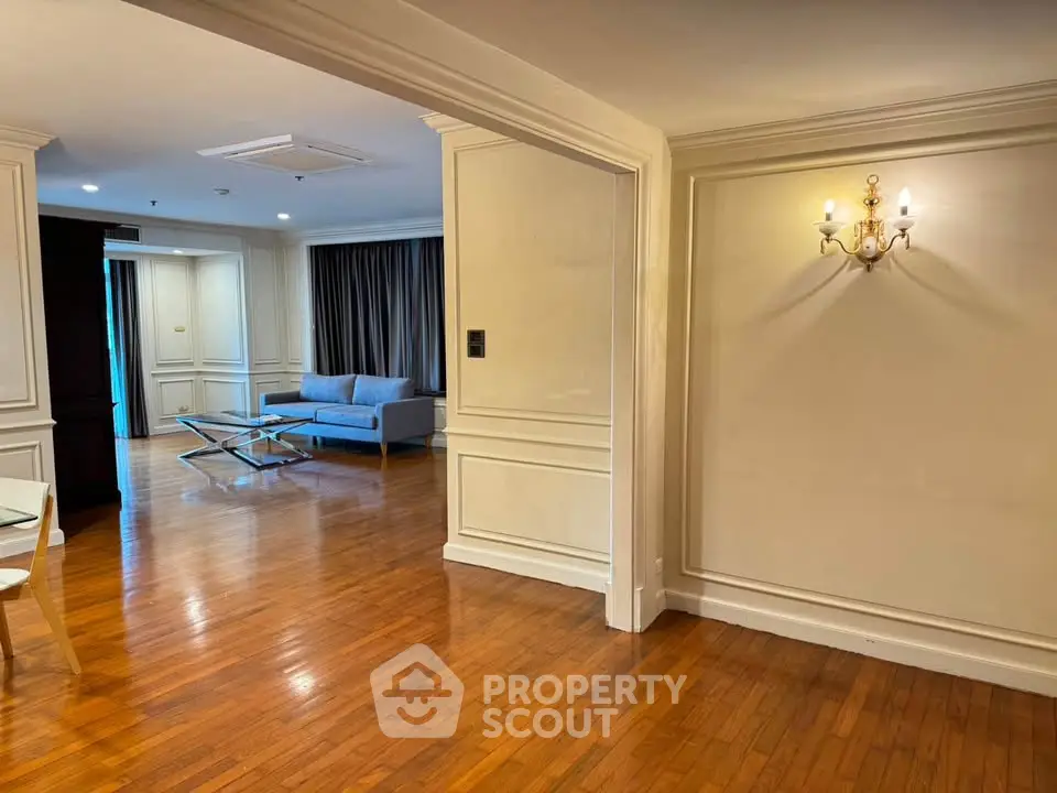 Spacious living room with elegant wooden flooring and modern lighting, perfect for stylish urban living.