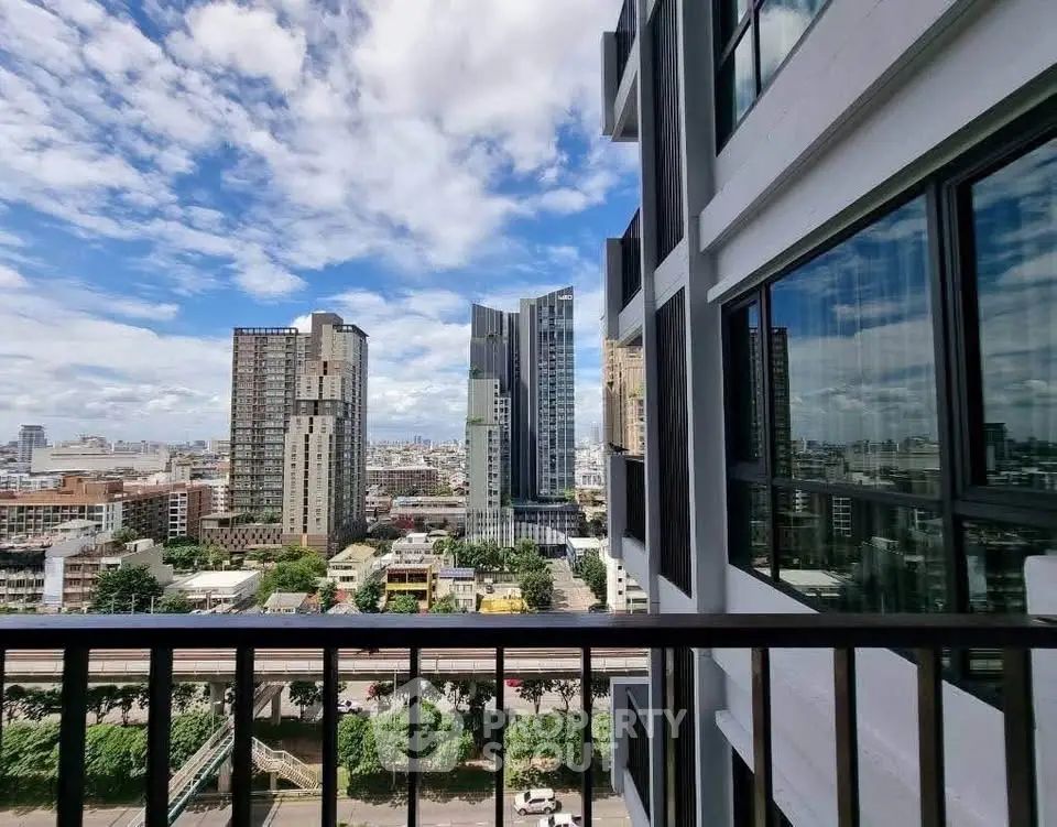 Stunning cityscape view from modern apartment balcony with clear blue skies.