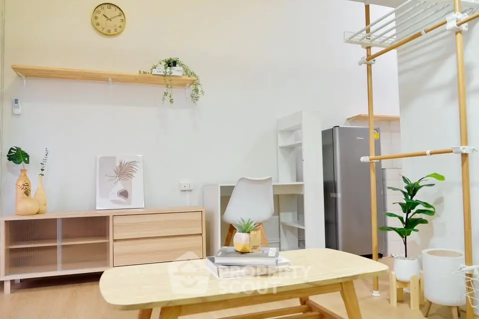Modern minimalist living room with stylish furniture and decor, featuring a sleek fridge and indoor plants.