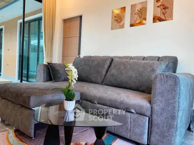 Modern living room with stylish gray sofa and glass coffee table, featuring elegant wall art and cozy ambiance.