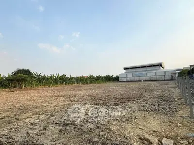 Expansive vacant land with potential for development, surrounded by lush greenery and clear skies.