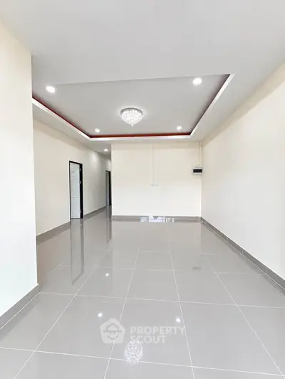 Spacious modern living room with elegant chandelier and glossy tiled flooring.