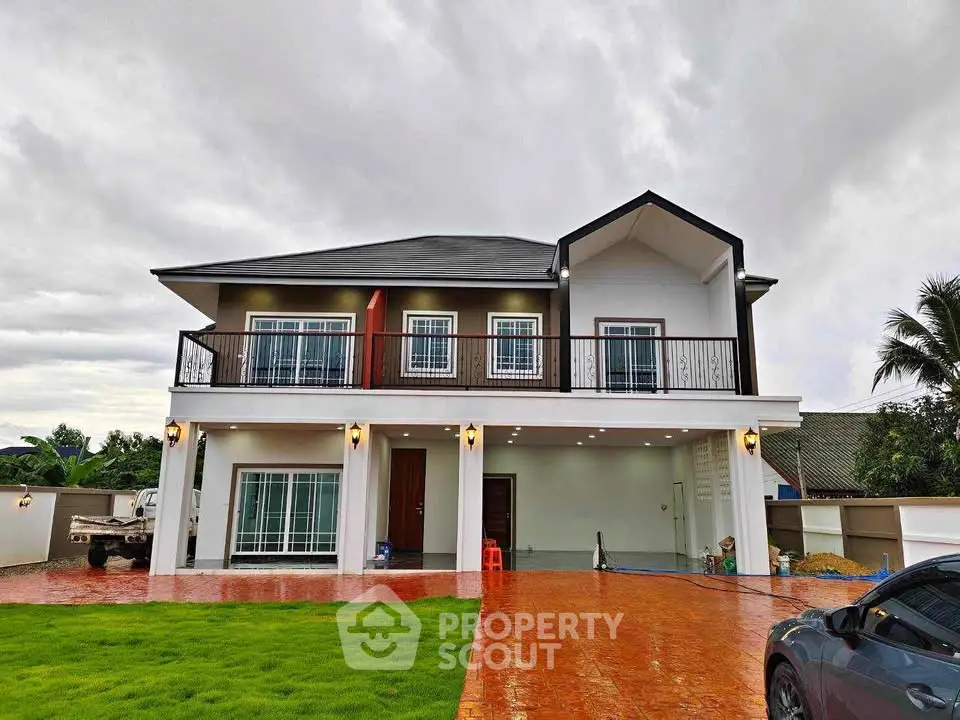 Stunning modern two-story house with spacious balcony and lush green lawn.