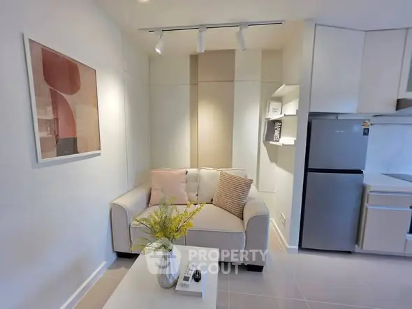 Modern living room with cozy sofa and sleek kitchen area in compact apartment.