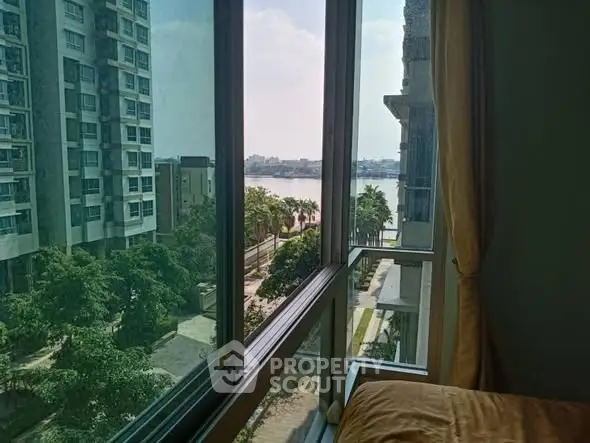 Stunning river view from modern apartment window, showcasing urban living with lush greenery.