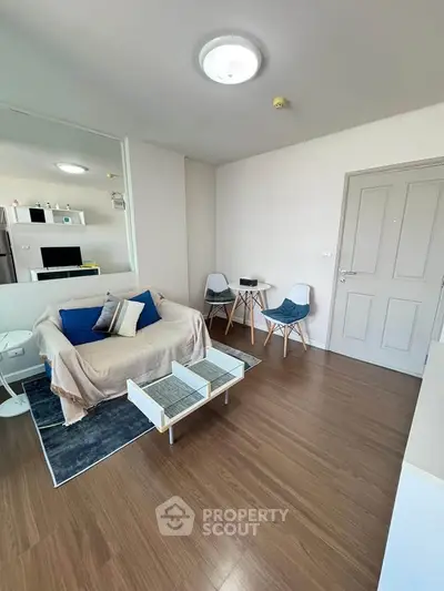 Modern living room with stylish decor and wooden flooring, featuring a cozy sofa and chic chairs.