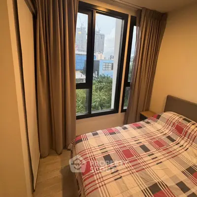 Cozy bedroom with large windows and city view, featuring modern decor and ample natural light.