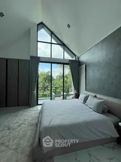 Luxurious bedroom with high ceilings and large windows offering stunning views of lush greenery.