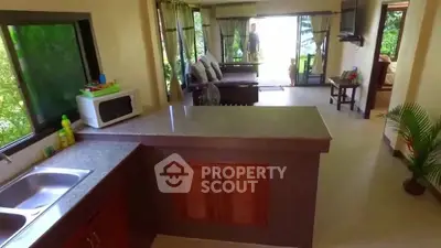 Spacious open-layout living room with modern kitchen and lush garden view.
