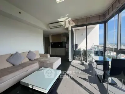 Spacious modern living room with large windows and city view, featuring a cozy sofa and sleek dining area.