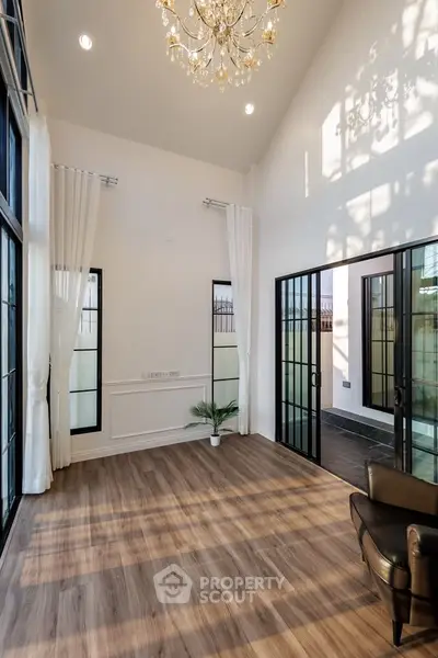 Elegant living room with high ceilings, chandelier, and large windows for natural light.