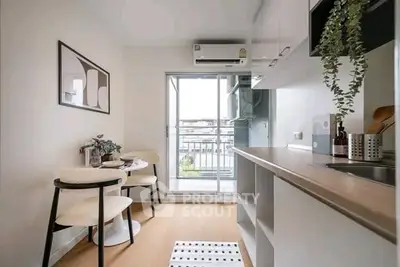 Modern kitchen with open layout and balcony view, featuring sleek cabinetry and dining area.