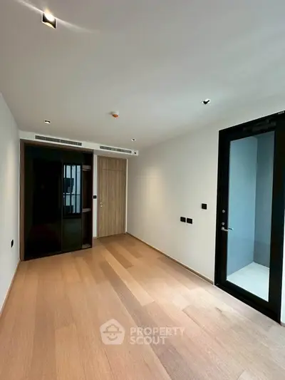 Spacious modern bedroom with wooden flooring and sleek black wardrobe