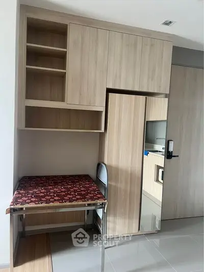 Modern compact study area with built-in wooden shelves and foldable table in a sleek apartment.