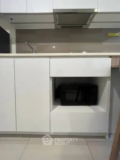 Modern kitchen with sleek cabinetry and built-in microwave, showcasing contemporary design and functionality.