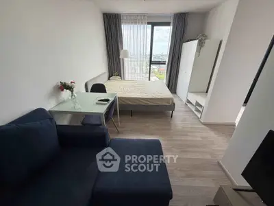 Modern studio apartment with cozy living area and large window view.
