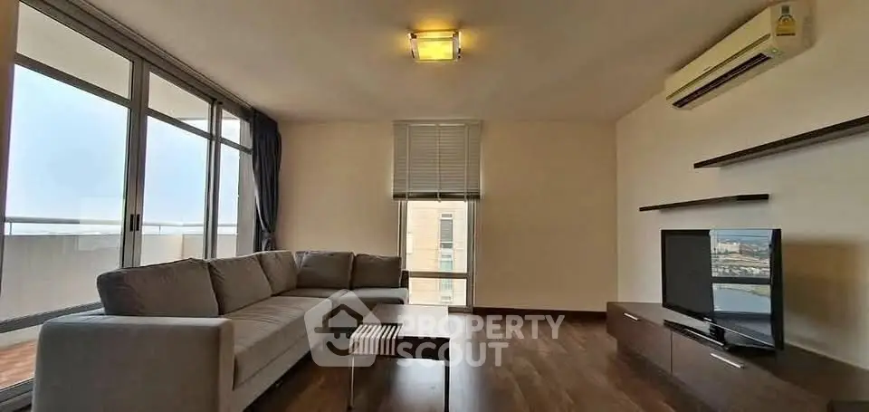 Spacious living room with modern sofa and large windows offering natural light.