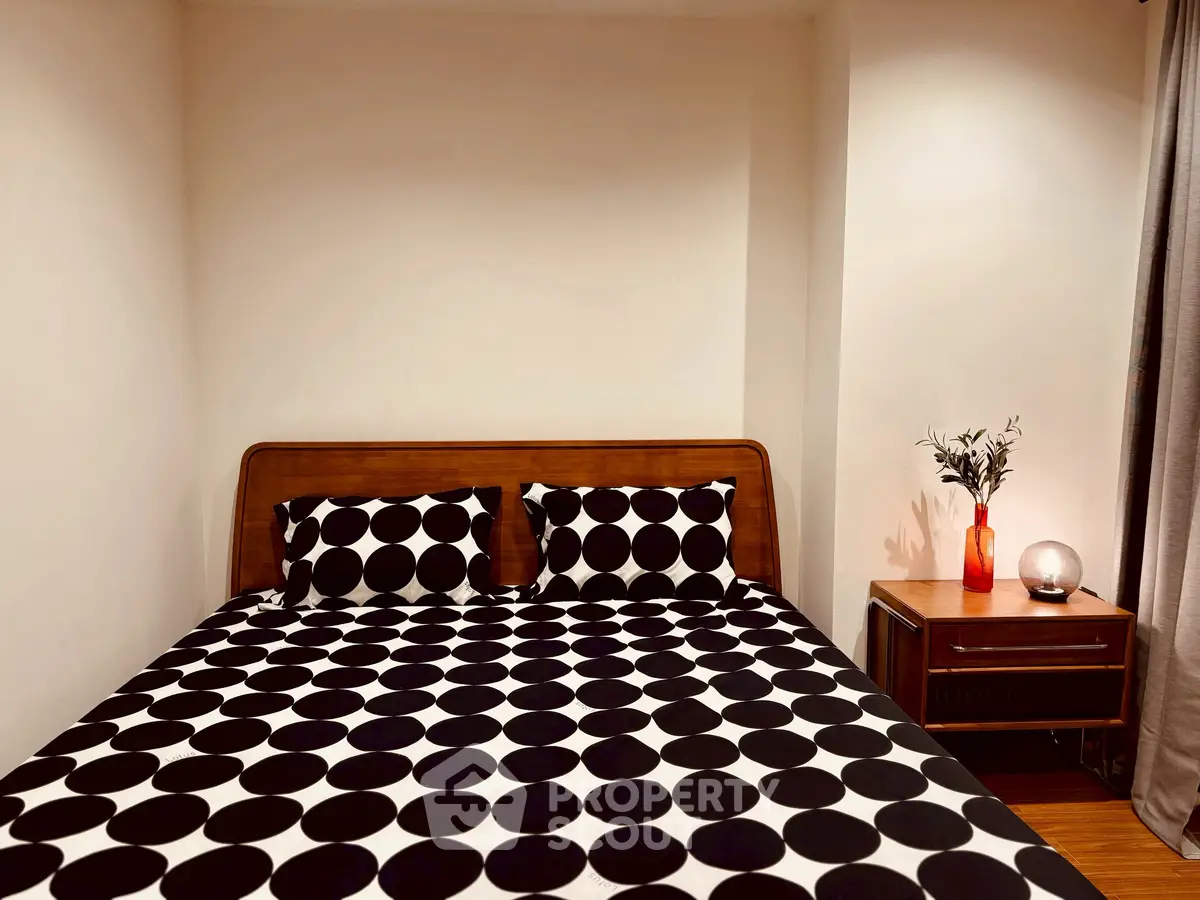 Cozy bedroom with stylish polka dot bedding and elegant wooden nightstand.