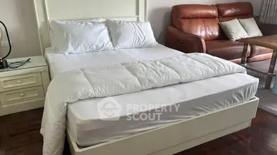 Spacious bedroom with cozy bed and elegant leather sofa, perfect for relaxation and comfort.