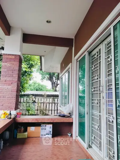 Charming outdoor patio with sliding glass doors and garden view, perfect for relaxation and entertaining.