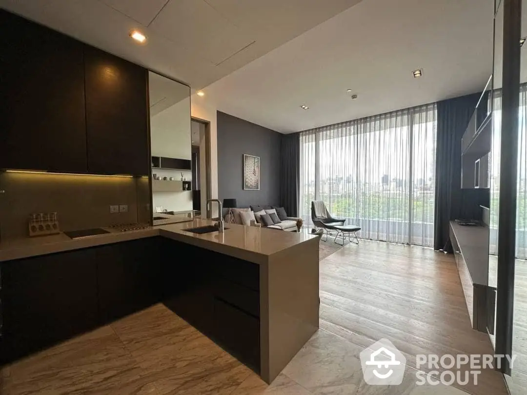 Sleek modern kitchen with open layout flows into a cozy living area, featuring high-end appliances, ample cabinetry, and a large window with natural light.