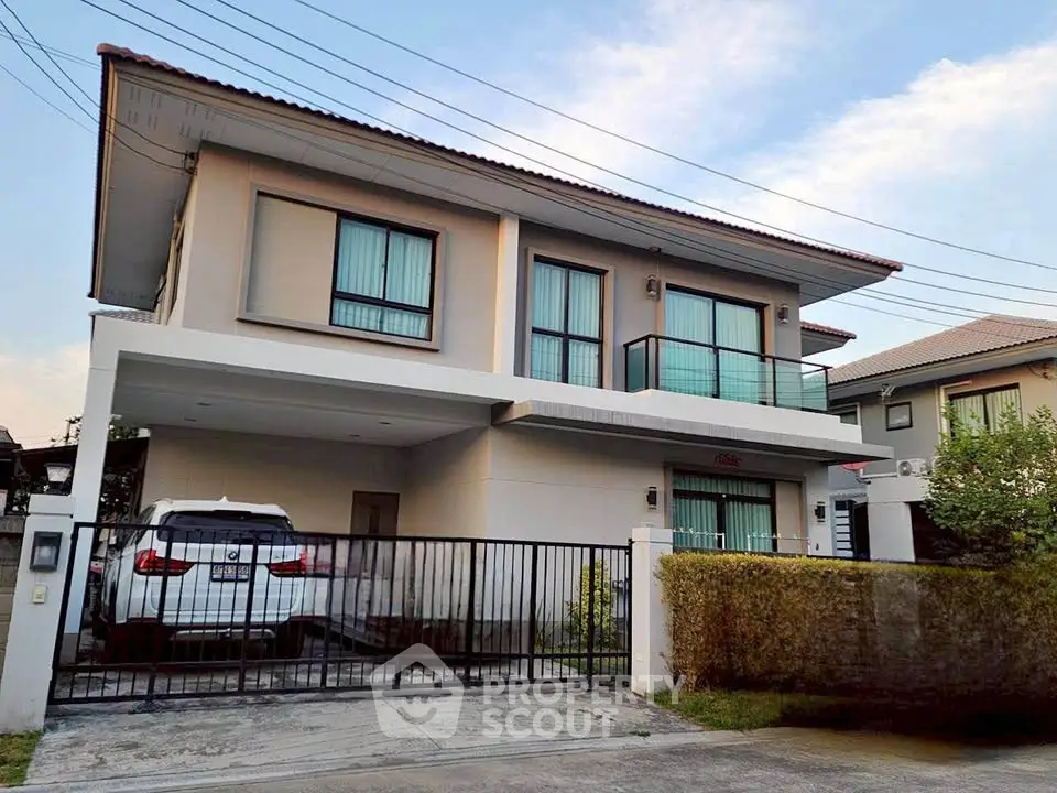 Modern two-story house with balcony and carport in a suburban neighborhood.