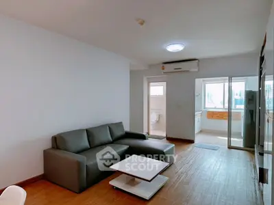 Spacious living room with modern sofa and open kitchen layout in urban apartment.
