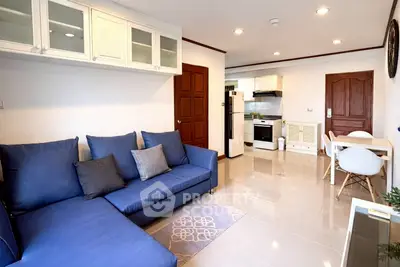 Modern living room with blue sofa and open kitchen layout in stylish apartment.