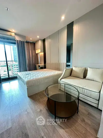 Modern bedroom with balcony view, featuring elegant furnishings and natural light.